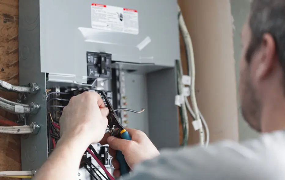 An electrician working on a homeowner's fuse box